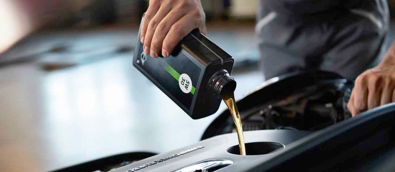 Imagine cu un specialist de service MINI turnând ulei de motor Imagine cu un specialist de service MINI turnând ulei de motor